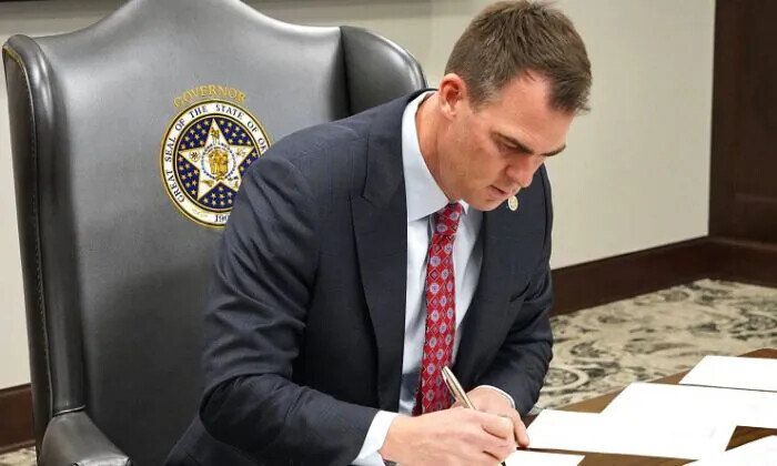 El gobernador de Oklahoma, Kevin Stitt, firma documentos en su despacho. Publicado el 14 de octubre de 2022. (Cortesía del Estado de Oklahoma)

