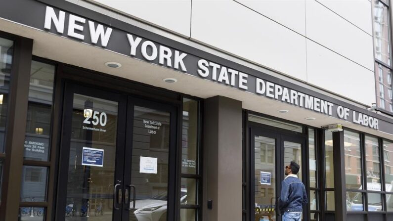Un hombre lee un cartel en la puerta de las oficinas cerradas del Departamento de Trabajo del Estado de Nueva York en Brooklyn. EFE/EPA/JUSTIN LANE
