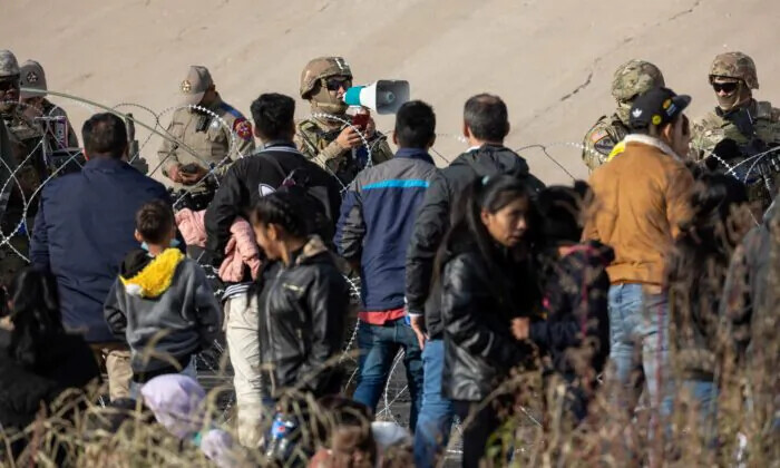 Un soldado de la Guardia Nacional de Texas habla con inmigrantes en un cruce fronterizo ilegal de alto tráfico a lo largo de Río Grande, en El Paso, Texas, el 20 de diciembre de 2022. (John Moore/Getty Images)
