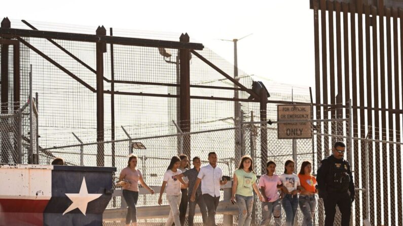 Inmigrantes ilegales abordan camionetas después de esperar a lo largo del muro fronterizo para entregarse a los agentes de la Patrulla Fronteriza de Aduanas y Protección Fronteriza (CBP) de EE.UU.; buscan el procesamiento de solicitudes de inmigración y asilo al cruzar el río Bravo hacia Estados Unidos en la frontera entre EE.UU. y México, en El Paso, Texas, el 11 de mayo de 2023. (Patrick T. Fallon/AFP vía Getty Images)
