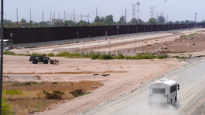 Un autobús sin distintivos se abre paso a lo largo de la valla fronteriza sur en San Luis, Arizona, aparentemente para recoger a solicitantes de asilo llegados de México. (Allan Stein/The Epoch Times)
