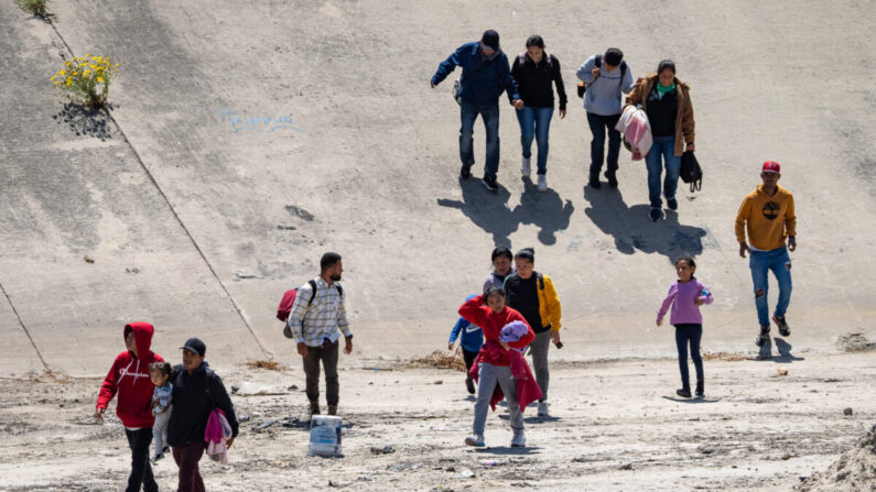 Migrantes cruzan el río Tijuana hacia la frontera con Estados Unidos en Tijuana, México, el 11 de mayo de 2023. (John Fredricks/The Epoch Times)
