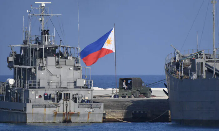 Una bandera filipina ondea junto a barcos de la armada anclados en la isla de Thitu, ocupada por Filipinas, en el disputado mar de China Meridional, el 21 de abril de 2023. (Ted Aljibe/AFP vía Getty Images)
