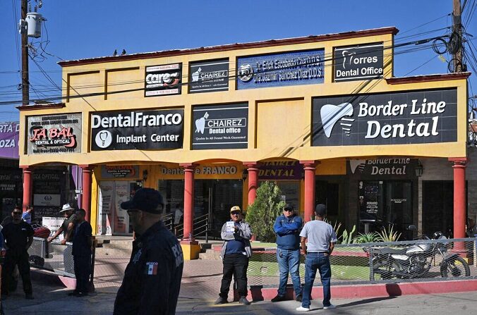 Un vendedor ambulante sostiene un cartel que anuncia servicios dentales mientras espera la llegada de turistas médicos estadounidenses en el puesto de control fronterizo, en Los Algodones, México, el 11 de abril de 2023. (Robyn Beck/AFP vía Getty Images)
