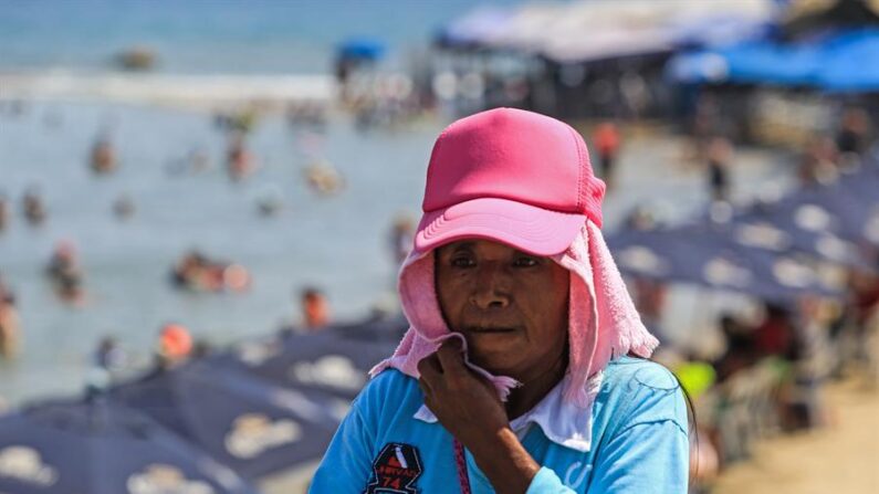 Una mujer se cubre del intenso calor en el balneario de Acapulco (México). EFE/David Guzmán