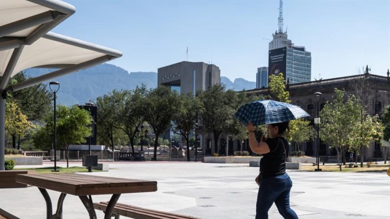 Una mujer sostiene una sombrilla para protegerse del sol, debido a las altas temperaturas que se registran en la ciudad de Monterrey (México). EFE/Miguel Sierra
