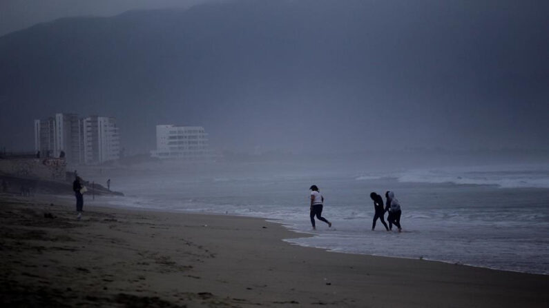 Personas juegan en la playa durante una tormenta, en una fotografía de archivo. EFE/ Alejandro Zepeda
