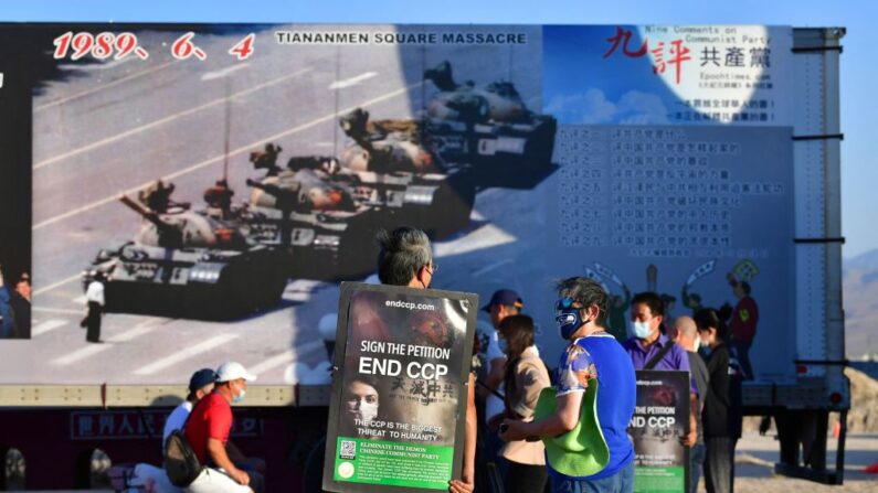 Activistas portan peticiones para acabar con el PCCh frente a la icónica fotografía del "Hombre del Tanque" expuesta en el Liberty Sculpture Park de la localidad californiana de Yermo, en el desierto de Mojave, el 4 de junio de 2021, donde la gente se congregó con motivo del 32º aniversario de la masacre de Beijing en la plaza de Tiananmen en 1989. (Frederic J. Brown/AFP vía Getty Images)