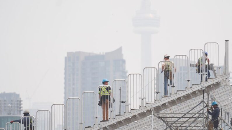 Trabajadores montan tribunas temporales para el Gran Premio de Toronto de la serie IndyCar, mientras el humo de los incendios forestales oscurece la Torre CN en Toronto, Ontario, el 28 de junio de 2023. (Geoff Robins/AFP vía Getty Images)