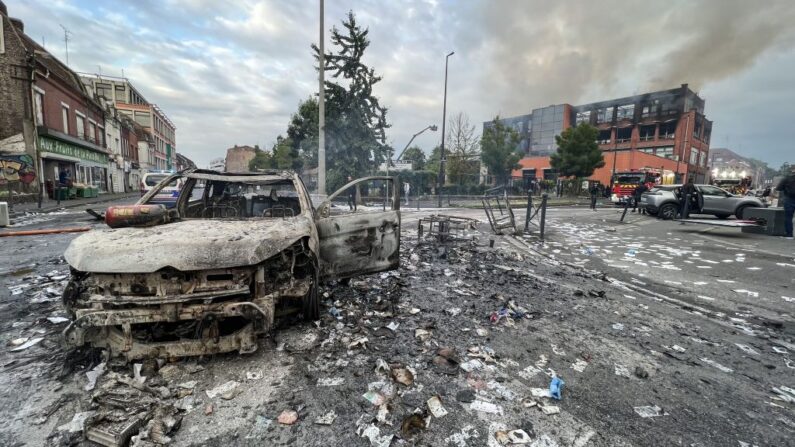 Un vehículo calcinado en una calle frente al edificio del grupo Tessi dañado por el fuego en el distrito Alma de Roubaix el 30 de junio de 2023, que fue completamente destruido por el fuego durante las protestas. (DENIS CHARLET/AFP vía Getty Images)