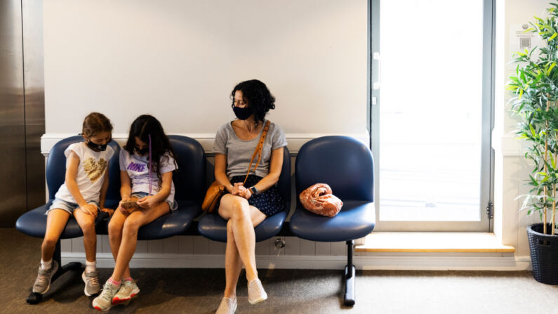 Maria Persic sentada con sus hijas Millie Persic (izq.) y Sofia Persic durante un periodo de observación tras la administración de la vacuna contra el COVID-19 de Pfizer en el Consultorio Médico Familiar de Sydney Road en Balgowlah, Sydney, Australia, el 11 de enero de 2022. (Jenny Evans/Getty Images)