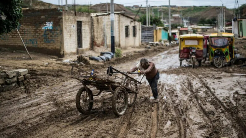 Un residente local empuja su carroza a través del lodo después de las inundaciones causadas por las lluvias en Perú, el 24 de marzo de 2023. (Ernesto Benavides/AFP/Getty Images)

