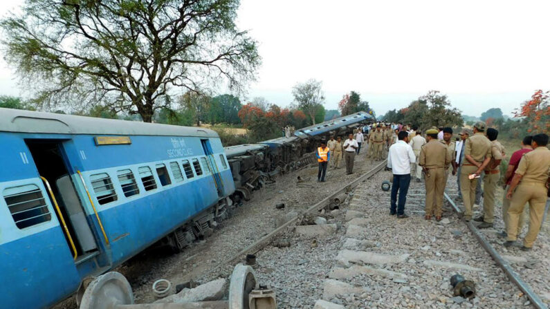 En una fotografía de archivo, trabajadores de rescate y funcionarios indios son observados por transeúntes mientras inspeccionan los vagones descarrilados del tren Mahakaushal Express en Mahoba, a unos 140 km al suroeste de Kanpur. (STR/AFP vía Getty Images)
