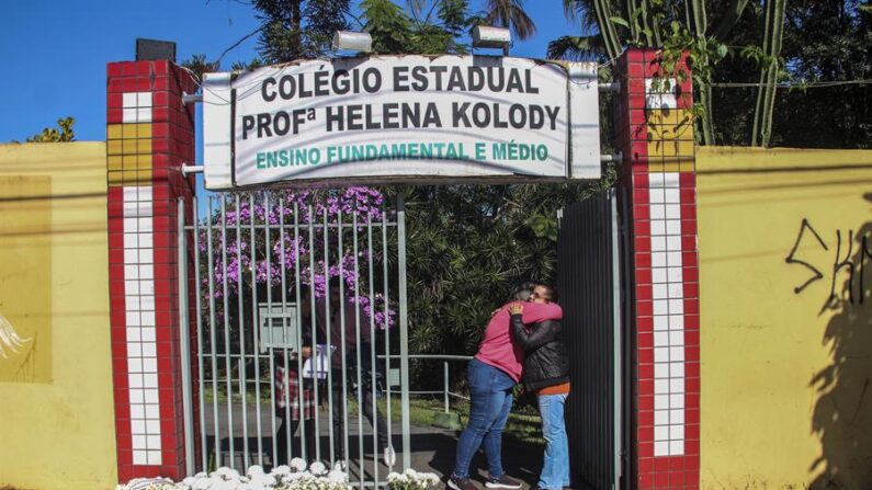 Personas ponen flores en la entrada a la escuela Profesora Helena Kolody, donde dos jóvenes fueron asesinados por un exalumno, en Cambé, Paraná (Brasil). EFE/ Filipe Barbosa
