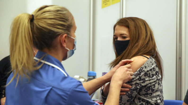 Caroline Nicolls recibe una inyección de la vacuna Moderna contra COVID-19 administrada por la enfermera Amy Nash, en el Estadio Madejski de Reading, Inglaterra, el 13 de abril de 2021. (Steve Parsons - WPA Pool/Getty Images)
