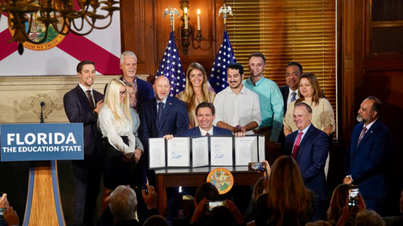El gobernador de Florida, Ron DeSantis, sostiene tres proyectos de ley recién firmados relacionados con la educación superior en el estado —incluido uno que prohíbe las prácticas de diversidad, equidad e inclusión (DEI)— en el New College de Sarasota, Florida, el 15 de mayo de 2023. (Cortesía de la Oficina del Gobernador de Florida)

