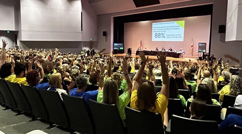 Los asistentes a una reunión del Consejo Escolar del Condado de Hernando, Florida, levantan la mano en señal de apoyo a un orador durante unos comentarios públicos el 30 de mayo de 2023. (Patricia Tolson/The Epoch Times)