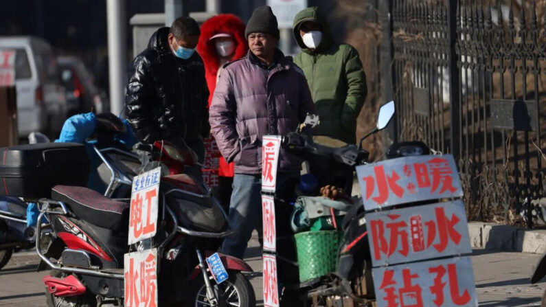 Trabajadores migrantes parados cerca de carteles que anuncian sus habilidades mientras esperan en una calle para ser contratados en Shenyang, en la provincia nororiental china de Liaoning, el 6 de febrero de 2023. (STR/AFP vía Getty Images)
