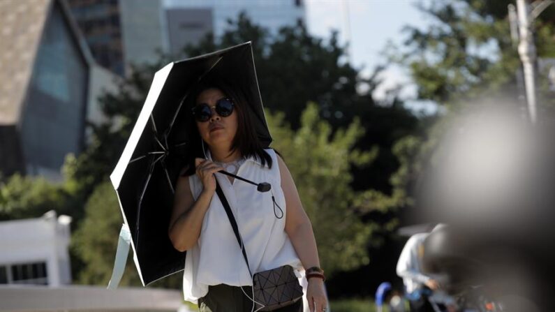 Fotografía de una mujer que se protege del sol con un paraguas en Beijing (China), la semana pasada. EFE/EPA/Wu Hao