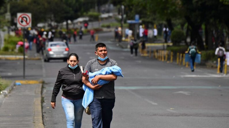 Una pareja con un bebé camina por una calle en Quito (Ecuador) el 29 de junio de 2022. (Martin Bernetti/AFP vía Getty Images)