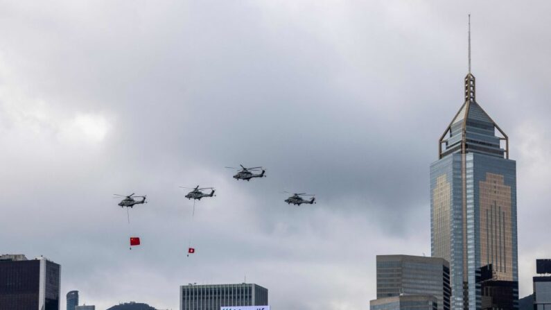 Helicópteros pasan con las banderas de Hong Kong y China durante una ceremonia de izado de banderas en Hong Kong el 1 de julio de 2023. (Isaac Lawrence/ AFP vía Getty Images)