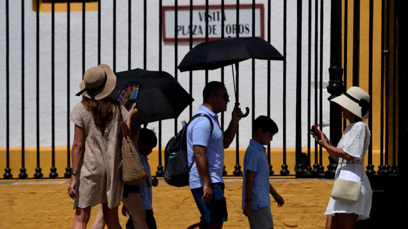 Turistas con abanicos y paraguas visitan el museo de la plaza de toros de la Real Maestranza de Sevilla el 10 de julio de 2023 durante una ola de calor. (Cristina Quicler/AFP vía Getty Images)