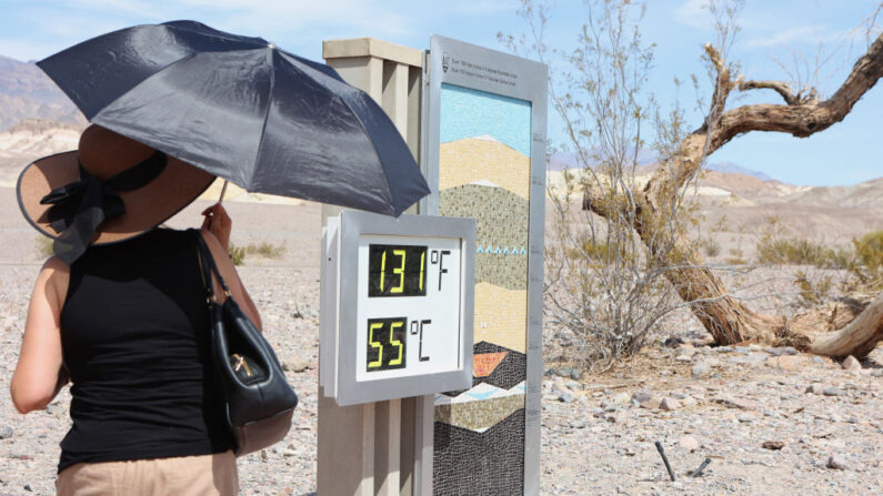 Una mujer se encuentra cerca de una pantalla digital de una lectura de calor no oficial en Furnace Creek Visitor Center durante una ola de calor en el Parque Nacional Death Valley en Death Valley, California, el 16 de julio de 2023. (Ronda Churchill/AFP vía Getty Images)