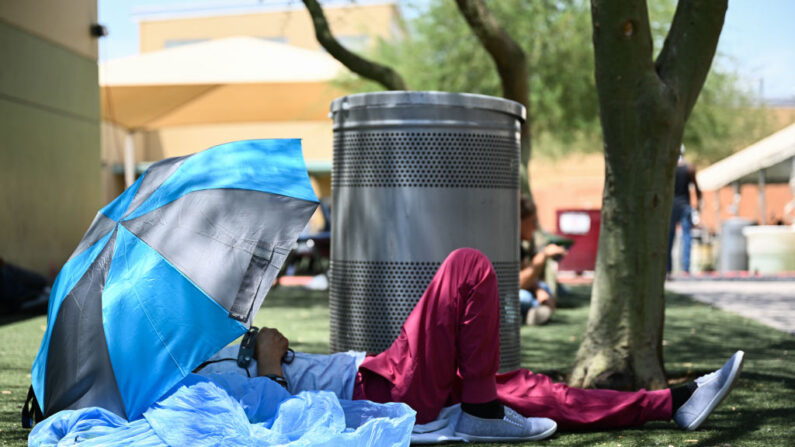 Un residente de Phoenix descansa bajo la sombra mientras busca protección contra el sol y el calor en el Campus de Servicios Humanos durante una ola de calor récord en Phoenix, Arizona, el 18 de julio de 2023. (Patrick T. Fallon/AFP vía Getty Images)
