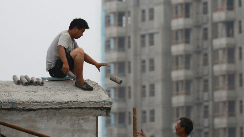 Dos obreros chinos trabajan en el techo de un edificio en un sitio de construcción en Beijing el 14 de julio de 2013. (Wang Zhao/AFP via Getty Images)