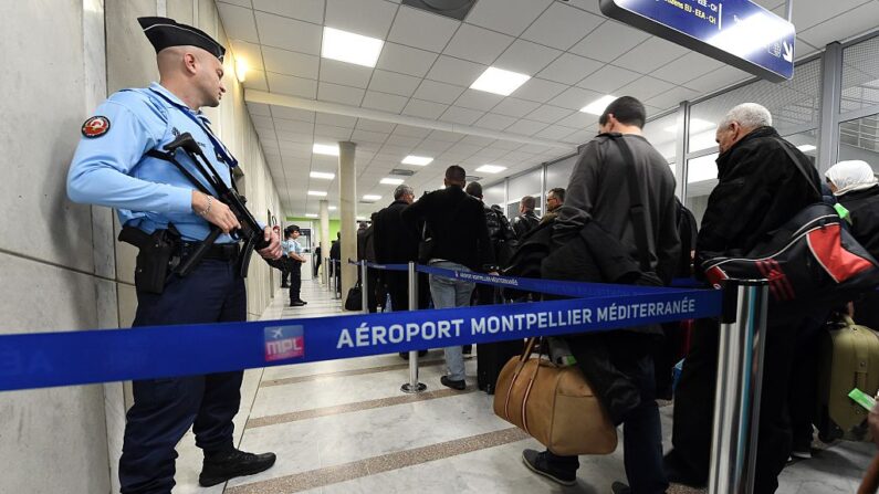 Un gendarme francés (iz) monta guardia en el aeropuerto de Montpellier, al sur de Francia, mientras los pasajeros pasan por el embarque el 20 de noviembre de 2015. (Pascal Guyot/AFP via Getty Images)