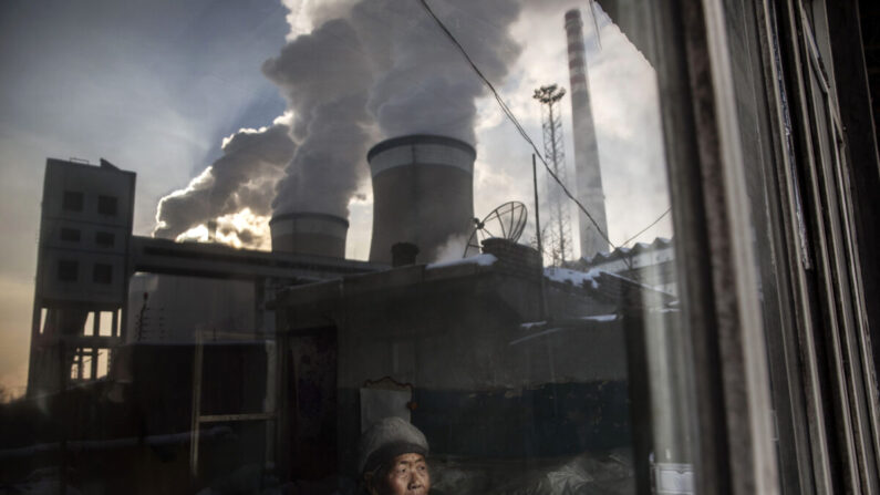 Una residente china mira por la ventana de su casa junto a una central eléctrica de carbón en la provincia de Shanxi, China, el 26 de noviembre de 2015. (Kevin Frayer/Getty Images)
