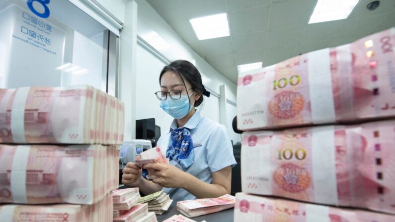 Un empleado bancario cuenta billetes de 100 yuanes en una ventanilla bancaria en Nantong, en la provincia oriental china de Jiangsu, el 13 de junio de 2023. (STR/AFP vía Getty Images)
