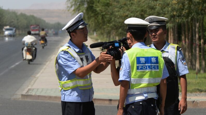La policía china detiene a un periodista en un puesto de control en la carretera que conduce a la ciudad uigur de Lukqun, región de Xinjiang, afectada por disturbios, el 28 de junio de 2013. (Mark Ralston/AFP vía Getty Images)