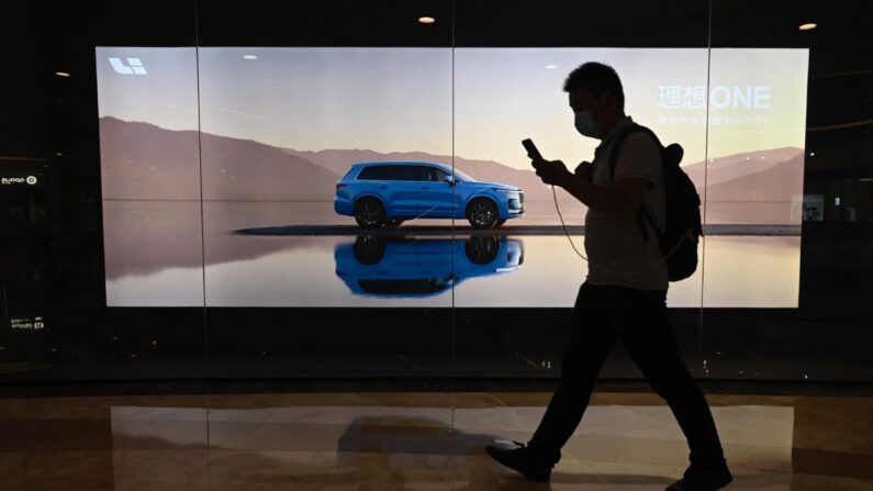 Un hombre pasa junto a una valla publicitaria que muestra un nuevo modelo del fabricante chino de coches eléctricos Li Auto, en un centro comercial de Beijing, el 12 de agosto de 2021. (Jade Gao/AFP vía Getty Images)