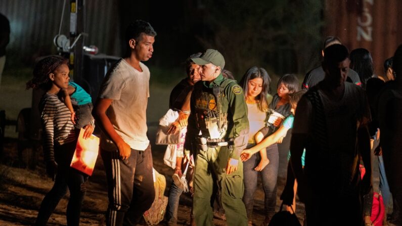 Inmigrantes ilegales esperan a ser conducidos por la Patrulla Fronteriza a una instalación de procesamiento para iniciar su proceso de solicitud de asilo en Eagle Pass, Texas, el 25 de junio de 2023. (Suzanne Cordeiro/AFP vía Getty Images)
