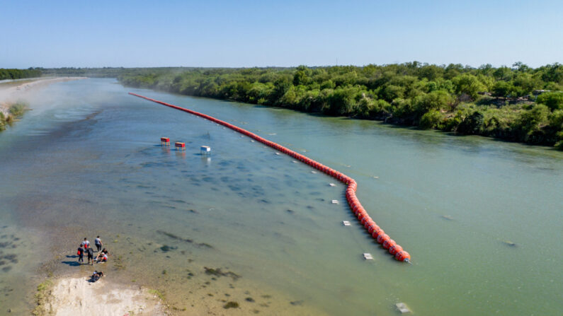 Personas descansan en un islote mientras intentan cruzar el río Grande hacia Estados Unidos, en Eagle Pass, Texas, el 18 de julio de 2023. (Brandon Bell/Getty Images)