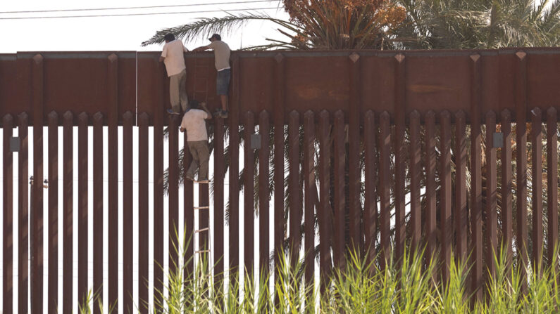 Migrantes utilizan una escalera de cuerda para escalar ilegalmente el muro fronterizo que separa Estados Unidos de México en El Centro, California, el 6 de octubre de 2022. (Allison Dinner/AFP vía Getty Images)