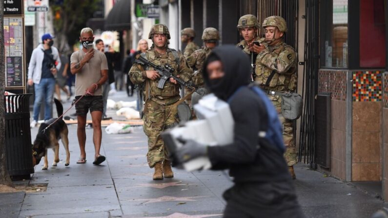 Un presunto saqueador con cajas de zapatos pasa corriendo junto a soldados de la Guardia Nacional en Hollywood, California, el 1 de junio de 2020. (Robyn Beck/AFP vía Getty Images)

