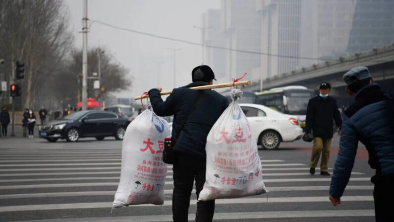 Un trabajador migrante cruza una calle después de llegar en un autobús a Beijing, el 10 de marzo de 2021. (Greg Baker/AFP vía Getty Images)
