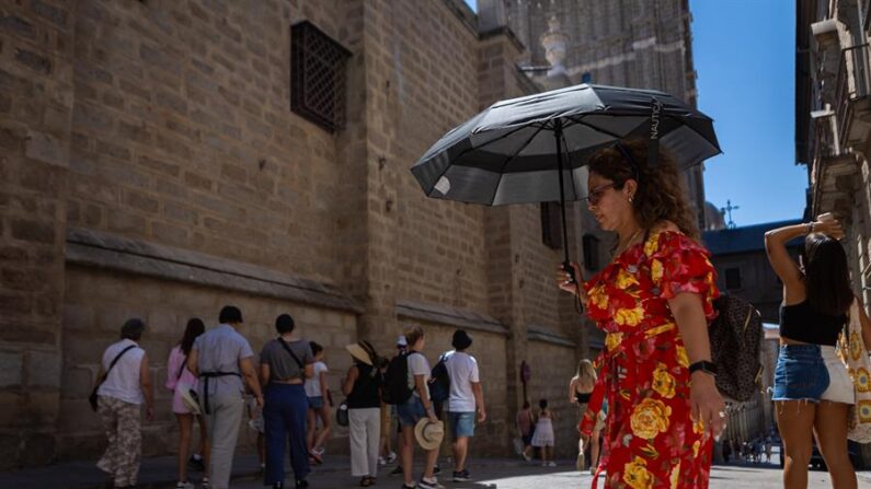Varios turistas se protegen del sol este lunes en Toledo que permanece con aviso naranja por altas temperaturas. EFE/Ángeles Visdómine