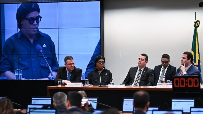 El exfutbolista brasileño Ronaldinho Gaúcho (c) declara el 31 de agosto de 2023 ante una comisión de la Cámara de Diputados de Brasil que investiga fraudes con pirámides financieras, en la sede del Congreso en Brasilia (Brasil). EFE/André Borges