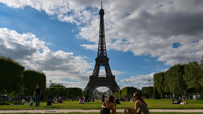 Turistas y parisinos sentados en el Campo de Marte frente a la Torre Eiffel en París (Francia) el 9 de agosto de 2023. (Miguel Medina/AFP vía Getty Images)