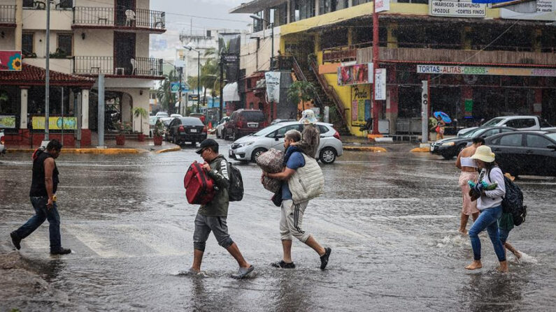 Personas caminan por una calle encharcada debido a las fuertes lluvias en Acapulco, estado de Guerrero, México. (EFE/David Guzmán)