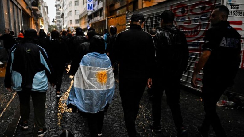 Un asistente con una bandera argentina camina por una calle al final de un acto para conmemorar el 213 aniversario de la Revolución de Mayo en Buenos Aires, el 25 de mayo de 2023. (LUIS ROBAYO/AFP vía Getty Images)