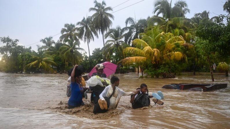 Los residentes cruzan la Ruta Nacional 2 sumergida en L'Acul en el Arrondissement de Léogâne 23 mi (o 37 km) al oeste de Puerto Príncipe, Haití, 3 de junio de 2023, durante las fuertes lluvias. (Richard Pierrin/AFP vía Getty Images)