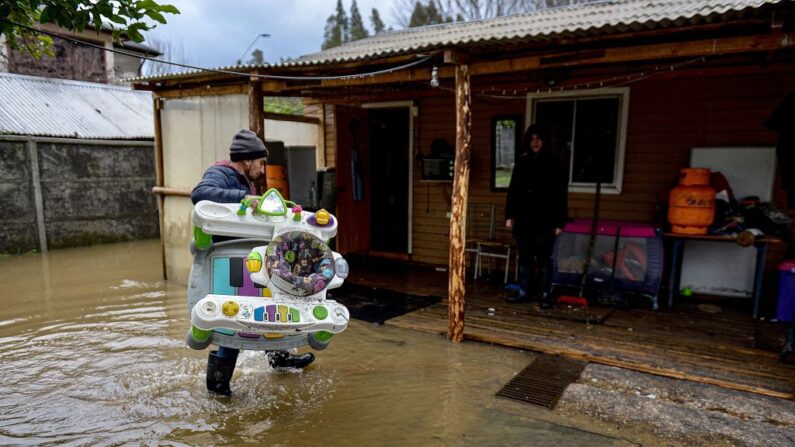 Personas sacan sus pertenencias de su casa después de que ésta fuera inundada por el desborde del río Biobío en Hualqui, a unos 30 km al sur de Concepción, Chile, el 25 de junio de 2023, tras las fuertes lluvias caídas en la región. (Guillermo Salgado/AFP vía Getty Images)