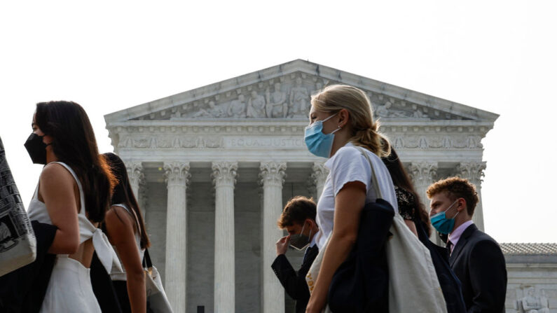 Un grupo de personas se pone mascarillas para protegerse de la contaminación atmosférica mientras pasan por delante del edificio de la Corte Suprema de EE.UU. el 29 de junio de 2023 en Washington, DC. (Anna Moneymaker/Getty Images)