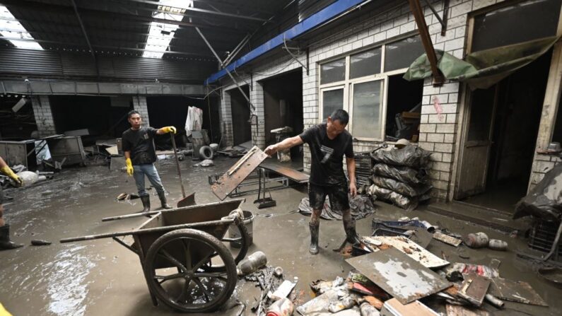 Unos trabajadores retiran barro y escombros de un almacén tras las inundaciones provocadas por las fuertes lluvias en la ciudad de Zhuozhou, en la provincia septentrional china de Hebei, el 9 de agosto de 2023. (Jade Gao/AFP vía Getty Images)