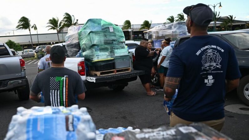 Voluntarios cargan palés de suministros y donaciones de ayuda procedentes de la isla hawaiana de Kauai, en camionetas, en la terminal de carga del aeropuerto de Kahului, tras los incendios forestales de Maui, en Kahului, Hawái, el 13 de agosto de 2023. (Patrick T. Fallon/AFP vía Getty Images)
