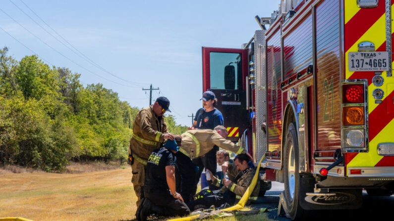Miembros de los Distritos de Servicios de Emergencia del Condado de Hays y de los Departamentos de Bomberos de Kyle y Buda descansan juntos mientras combaten un incendio forestal durante una advertencia de calor excesivo en el Condado de Hays, Texas, el 8 de agosto de 2023. (Brandon Bell/Getty Images)